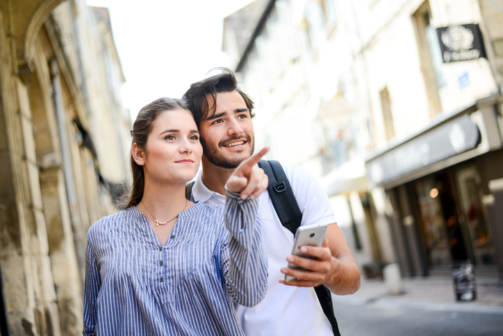 Cute young couple traveling through a city and using their cell for directions.