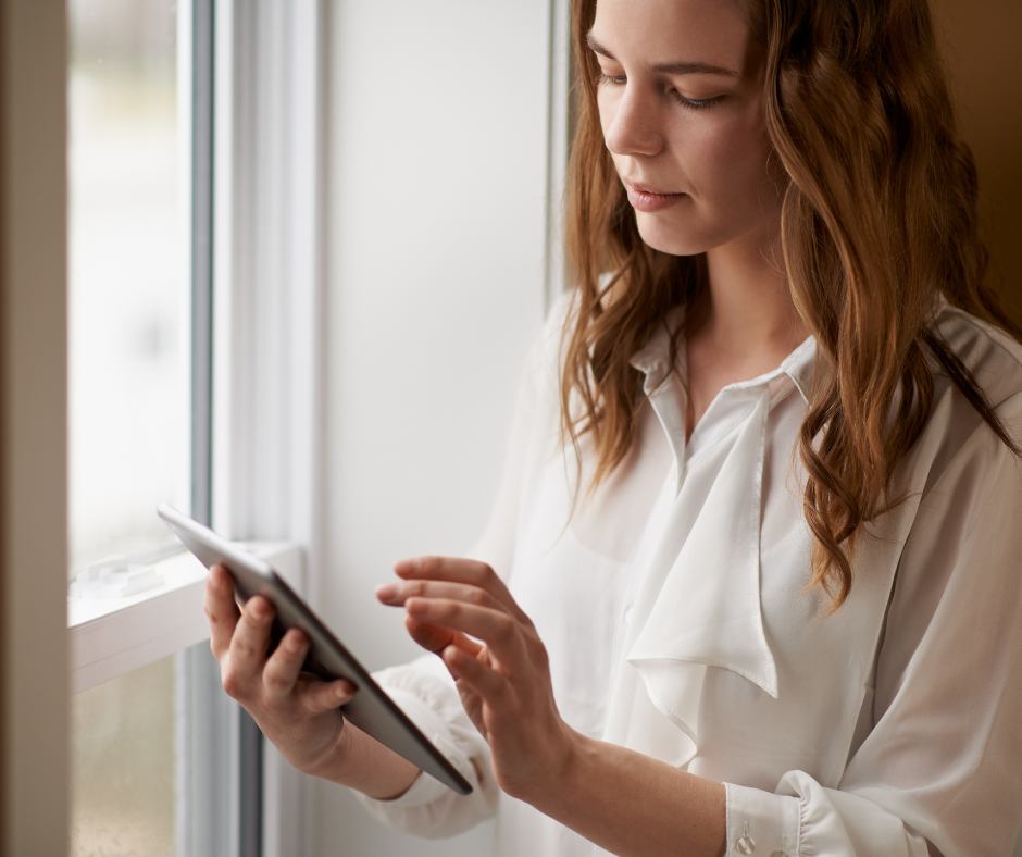 a woman in a white blouse touches a tablet with her hand