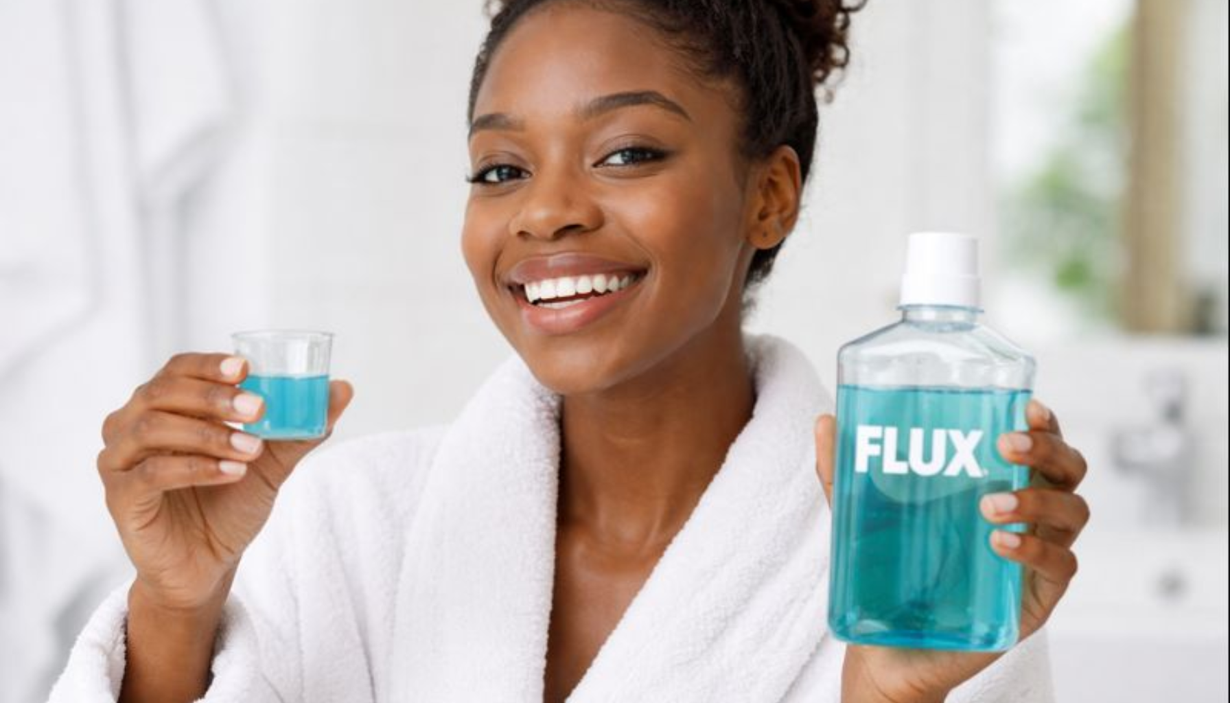 Kvinne bruker munnskyll hjemme, viser daglig munnhygiene for sunnere tenner og tannkjøtt.