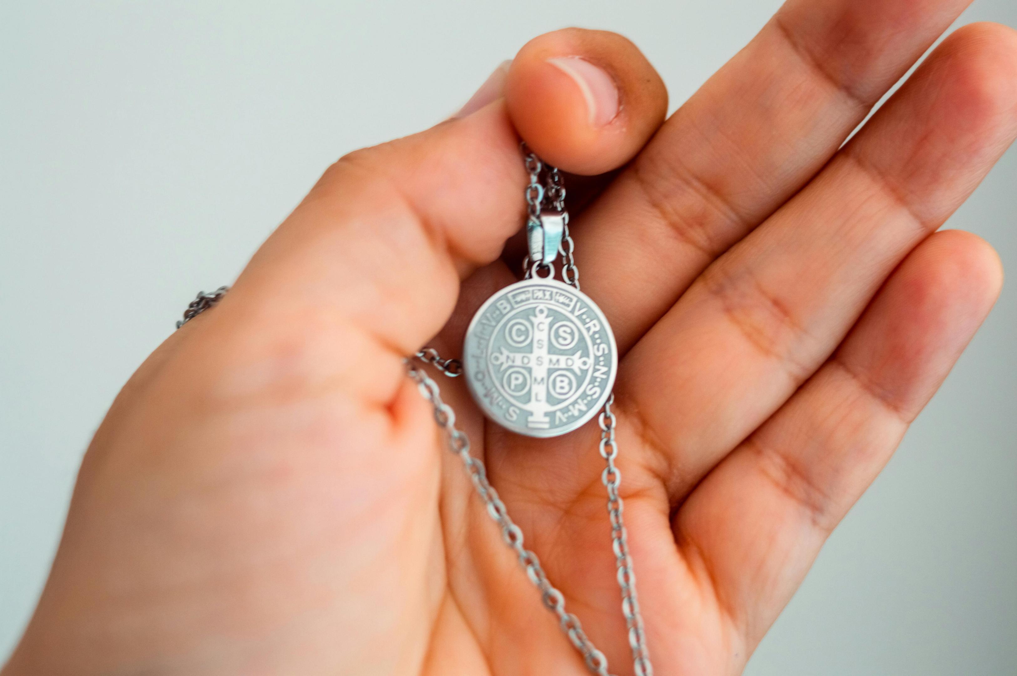 A hand holding a pendant necklace