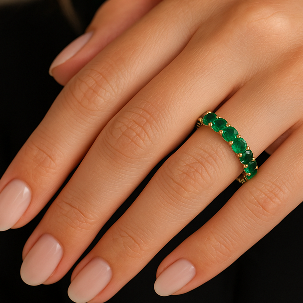 Merginos ranka su prabangiu žiedu juostele iš aukso, inkrustuotu žaliais smaragdais, pabrėžiančiais akmenų grožį