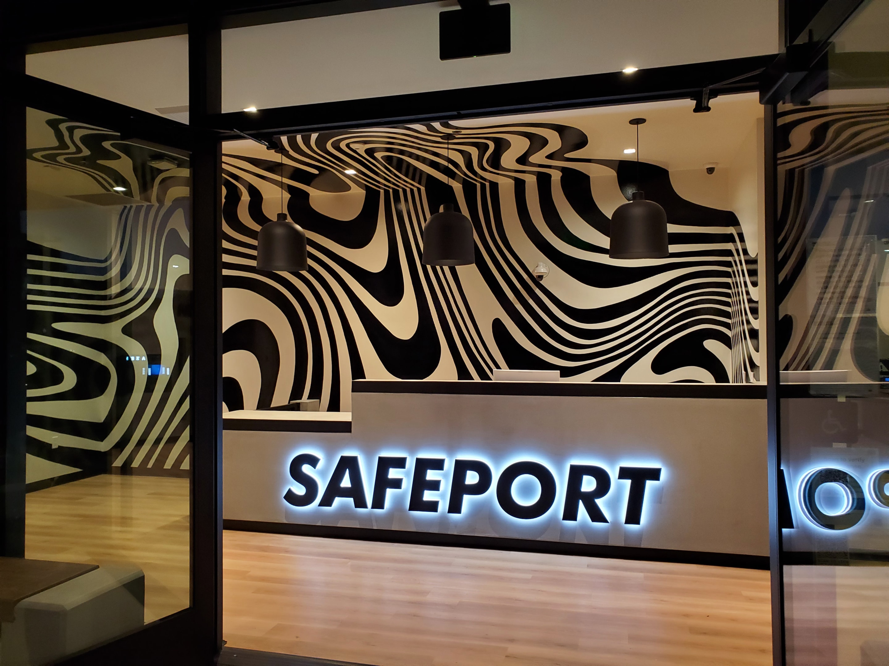 This custom interior halo-lit channel letter sign for Safeport in Oxnard, CA, adds a sleek, modern glow that perfectly complements the custom wall graphics wrapping from floor to ceiling.