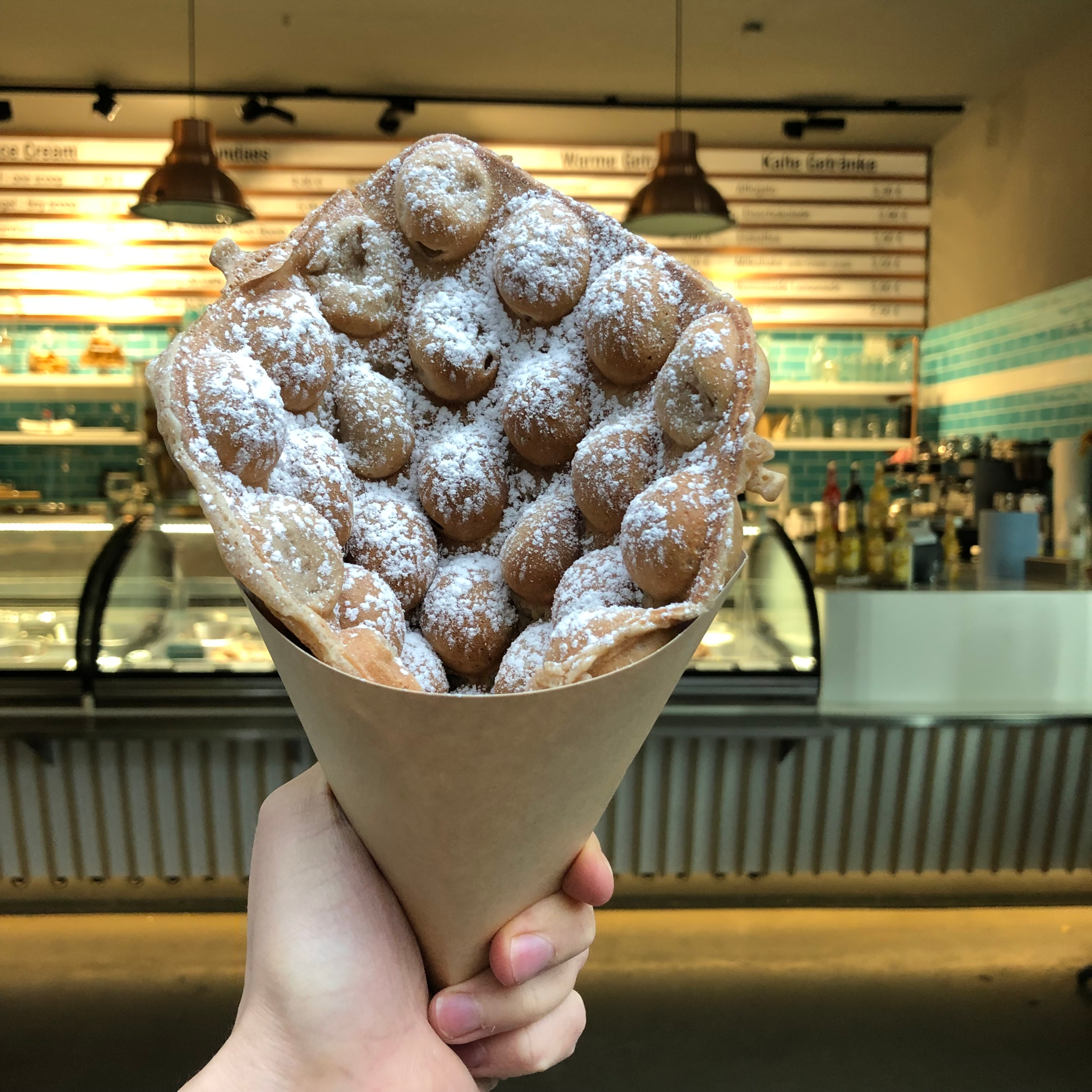 Serving bubble waffles in a cone shape with powdered sugar