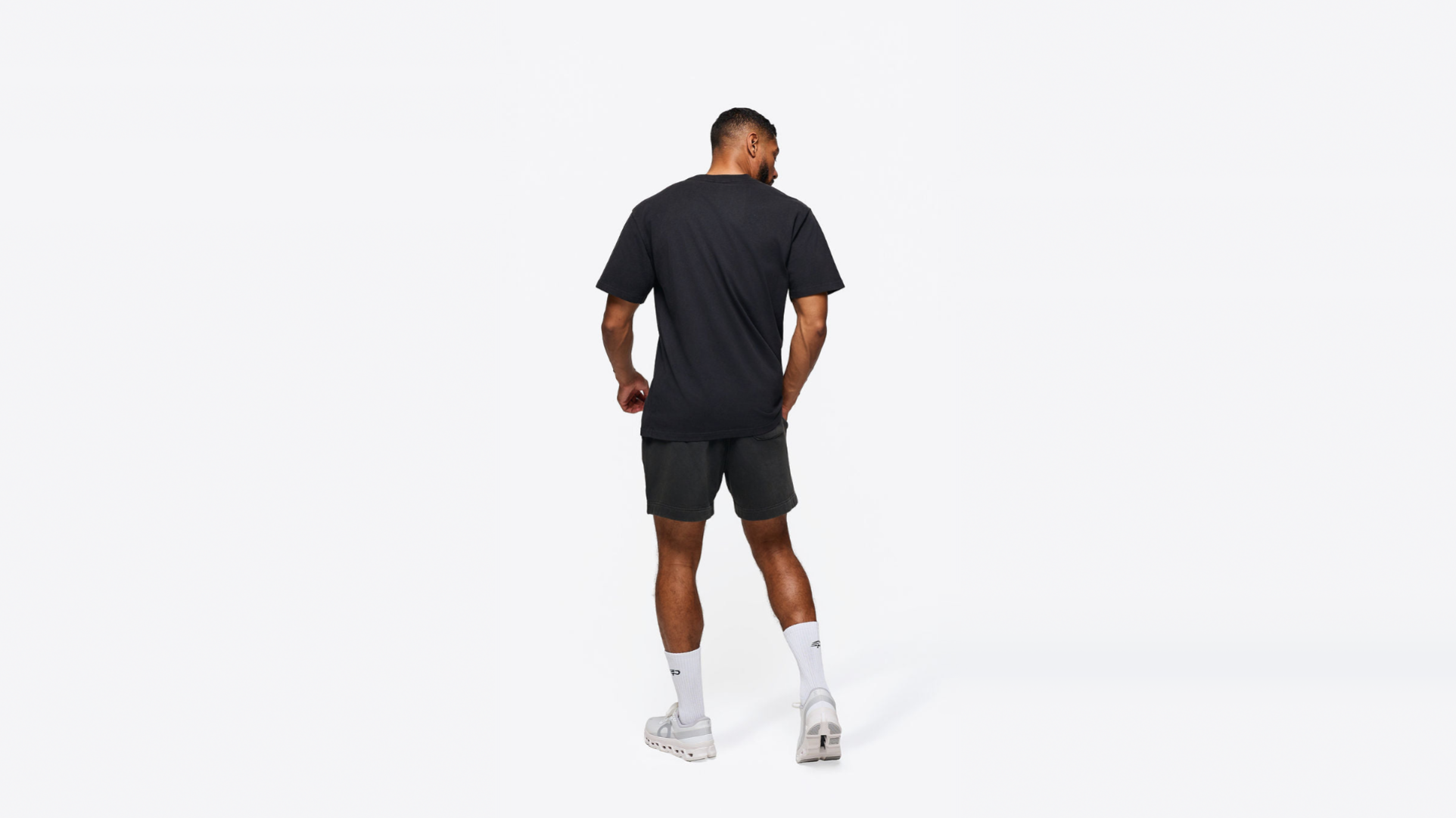 A man is reaching overhead for a padel smash on an outdoor court, dressed in a fitted performance tee designed for maximum performance and breathability. His attire showcases technical fabrics that enhance mobility and moisture management, perfect for intense rallies in competitive play.