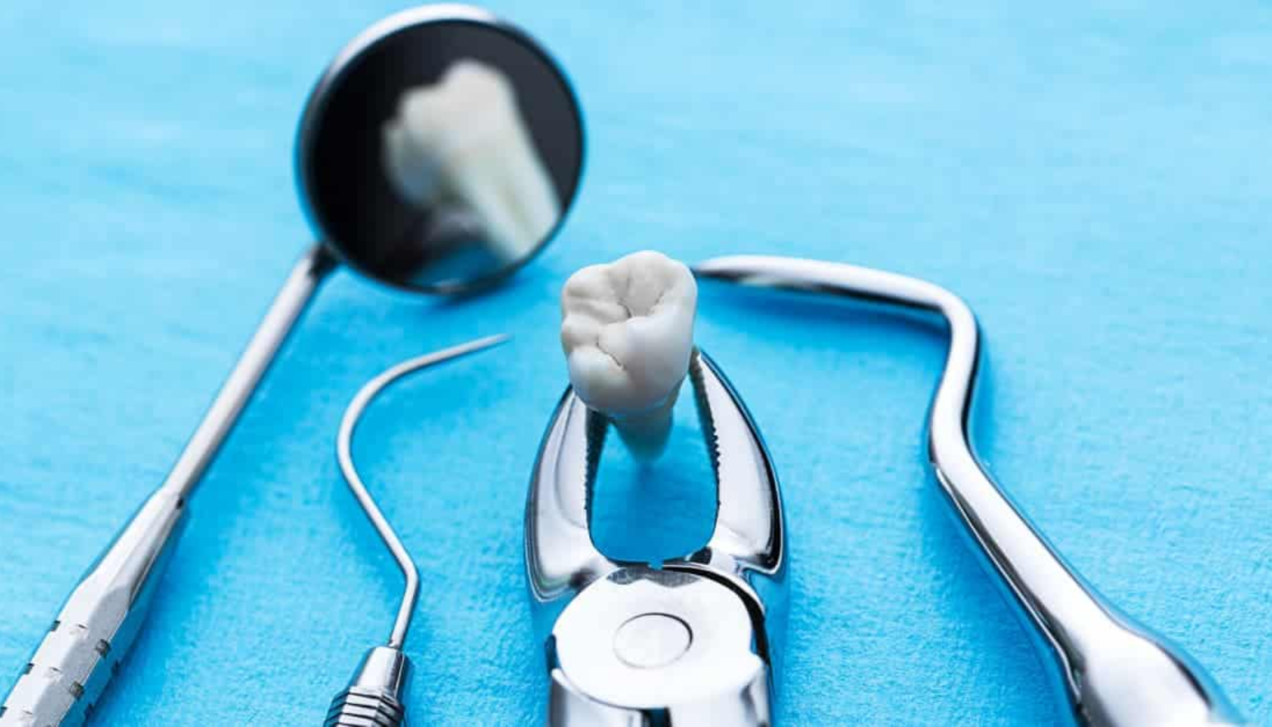Tann som er fjernet med tang, omgitt av tannlegeinstrumenter på blå bakgrunn.