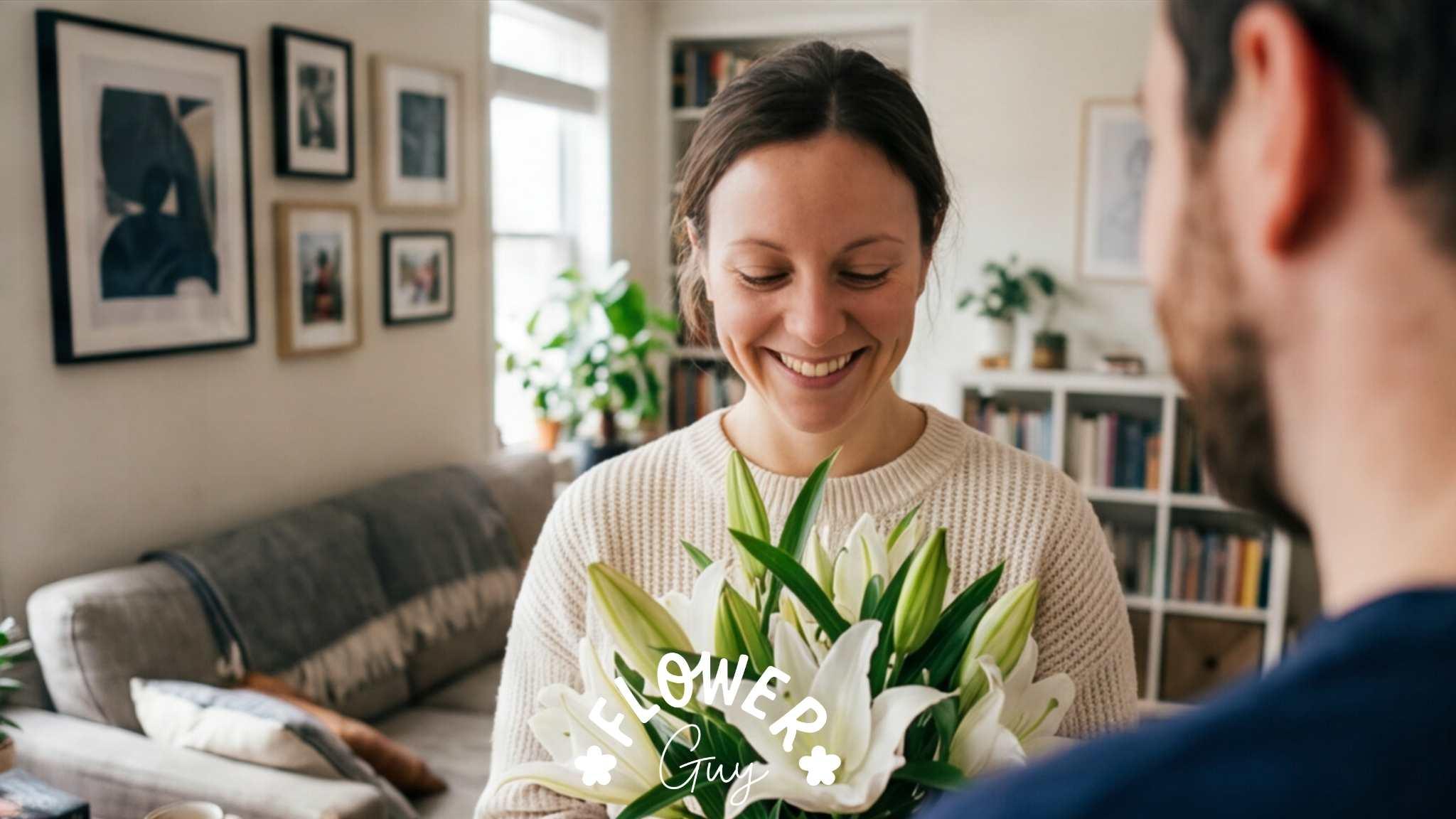 Woman receiving white lily bouquet from her partner in a lounge, smiling moment, hand-tied lilies, Flower Guy Cape Town and Joburg