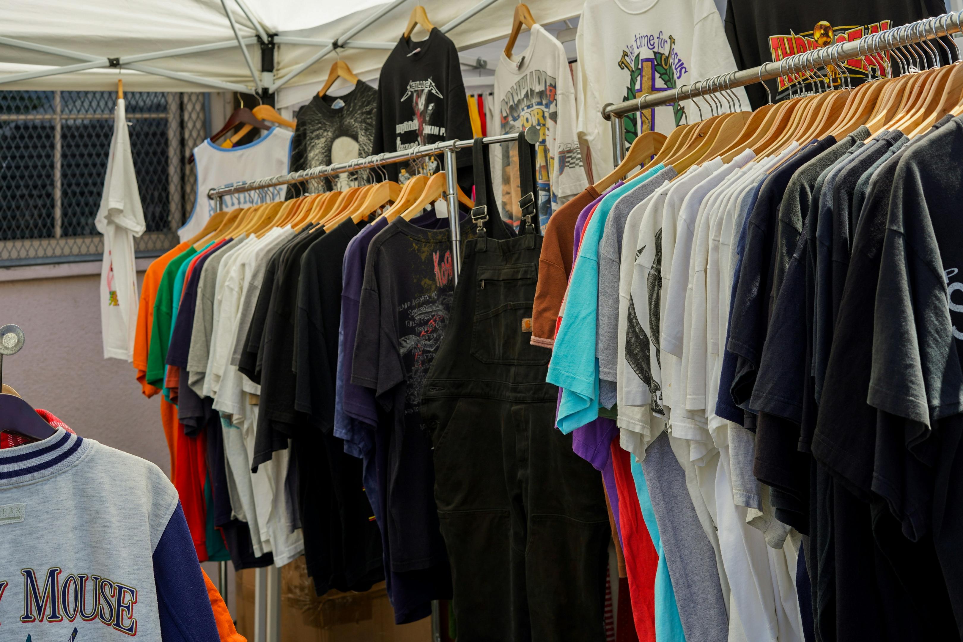 Vintage clothing racks full of tshirts at an outdoor market.