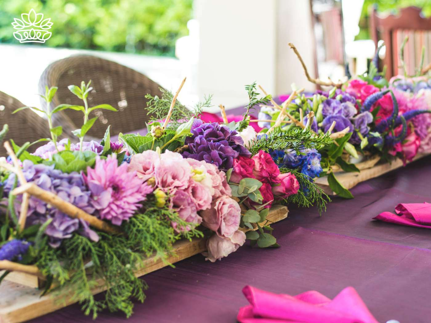 A lush and artful floral arrangement stretching across a banquet table, featuring a harmonious mix of hydrangeas and pink blooms, crafted by the skilled online florist at Fabulous Flowers and Gifts.