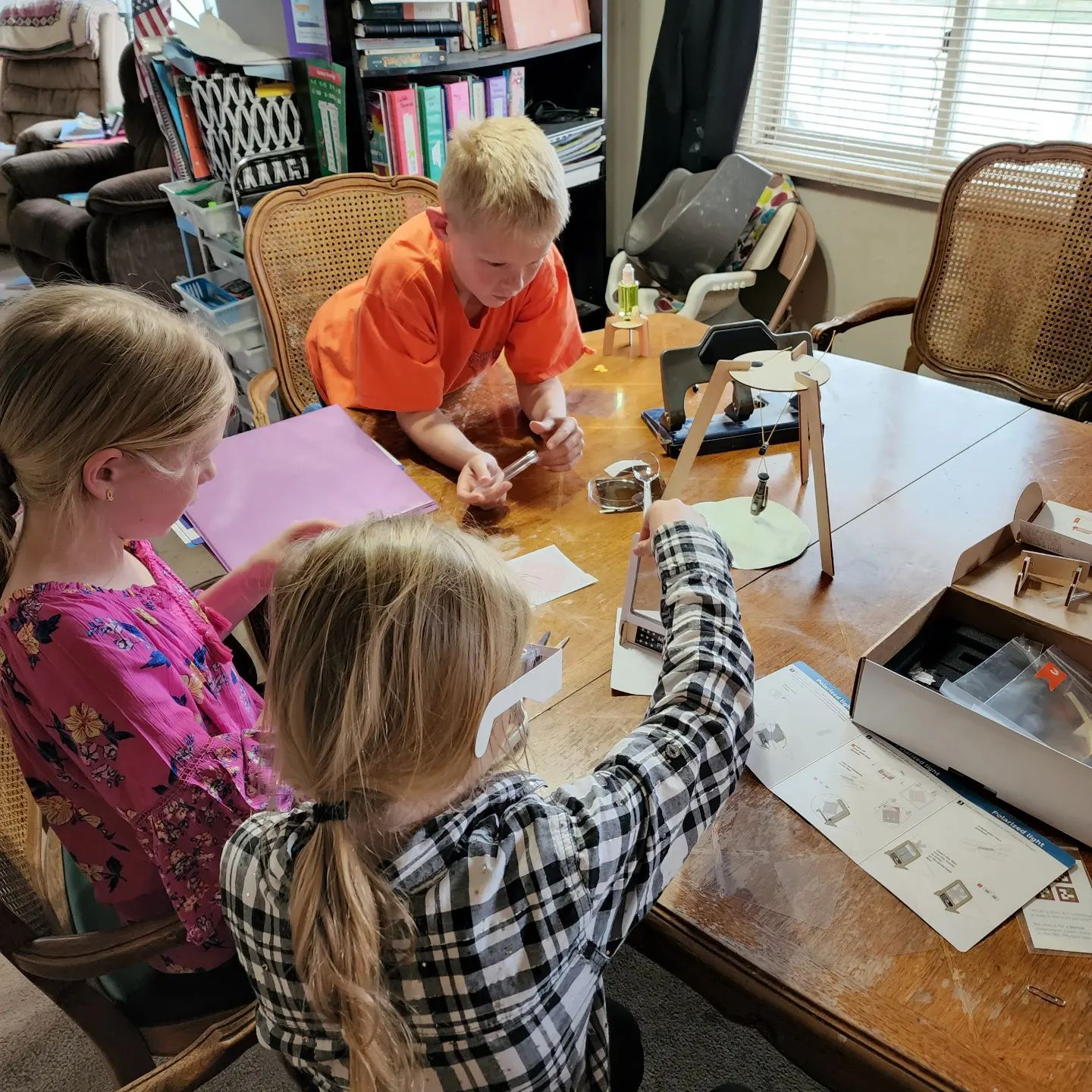 A group of happy children playing and learning with science kits for 5 year olds in a classroom setting.