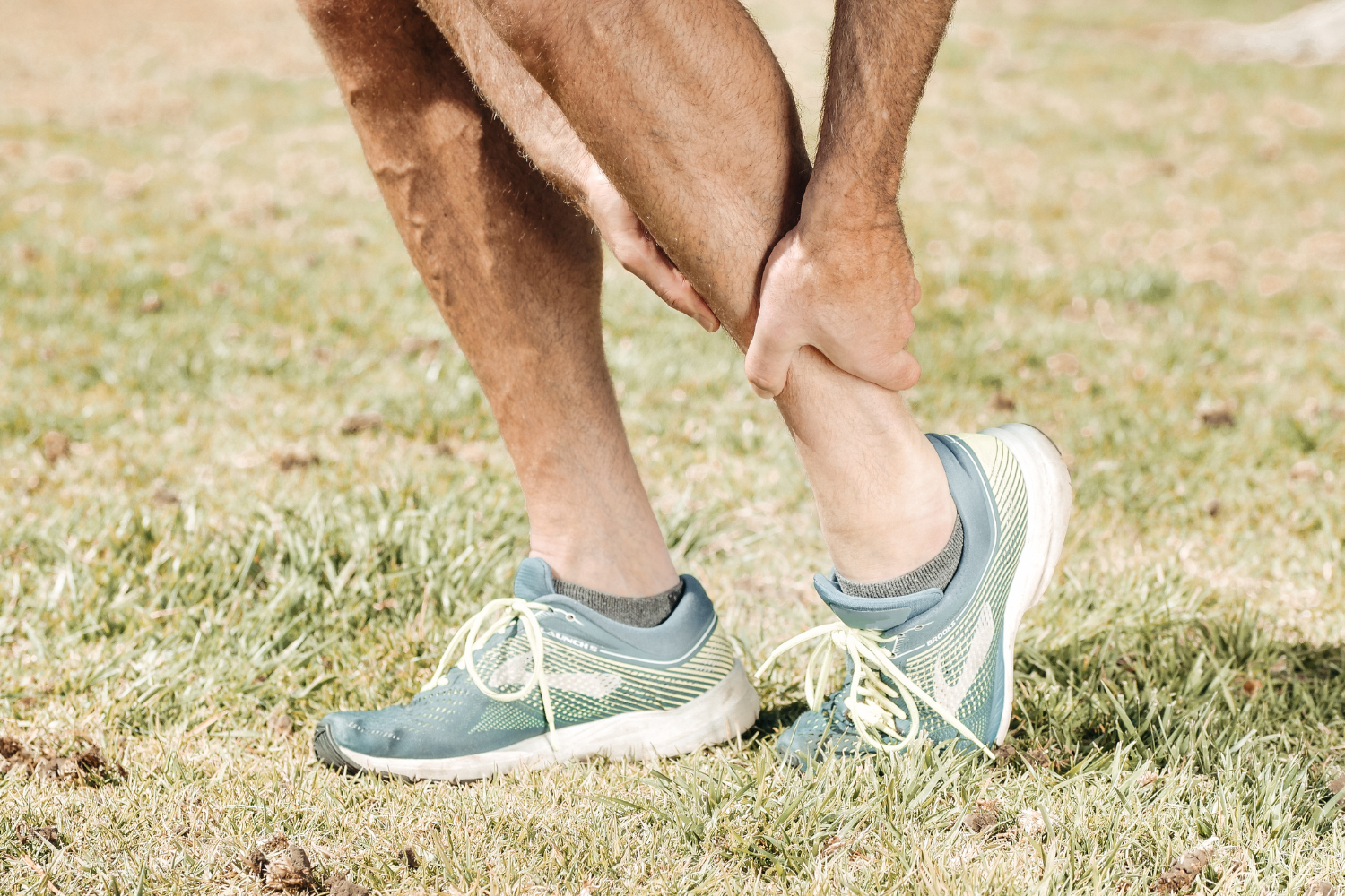 Person holding calf muscle in discomfort.
