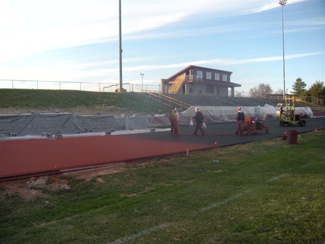 Pro Track & Tennis Team actively resurfacing a running track, applying new material to create a smooth, durable, and high-performance athletic surface.