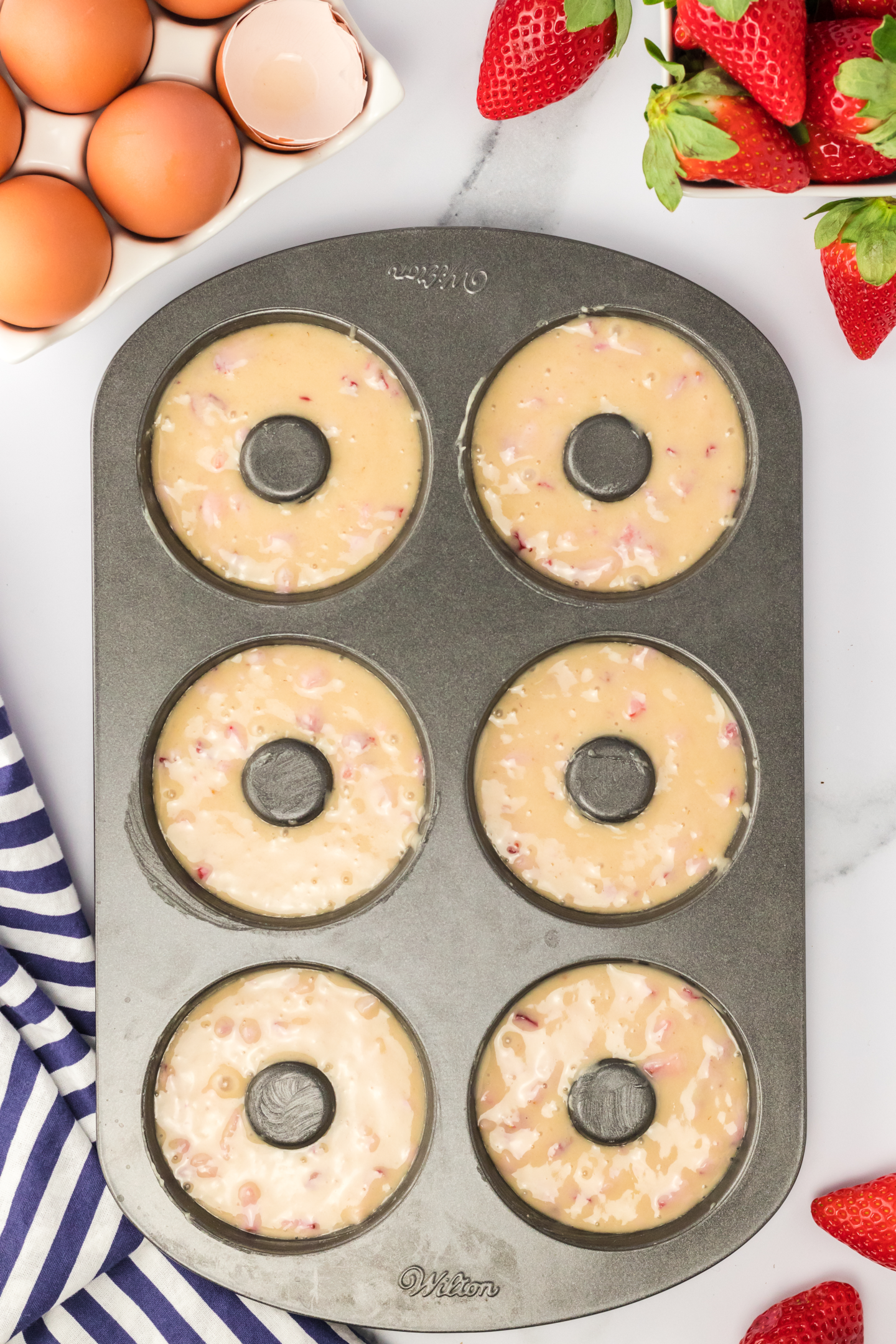 six unbaked strawberry donuts in pan