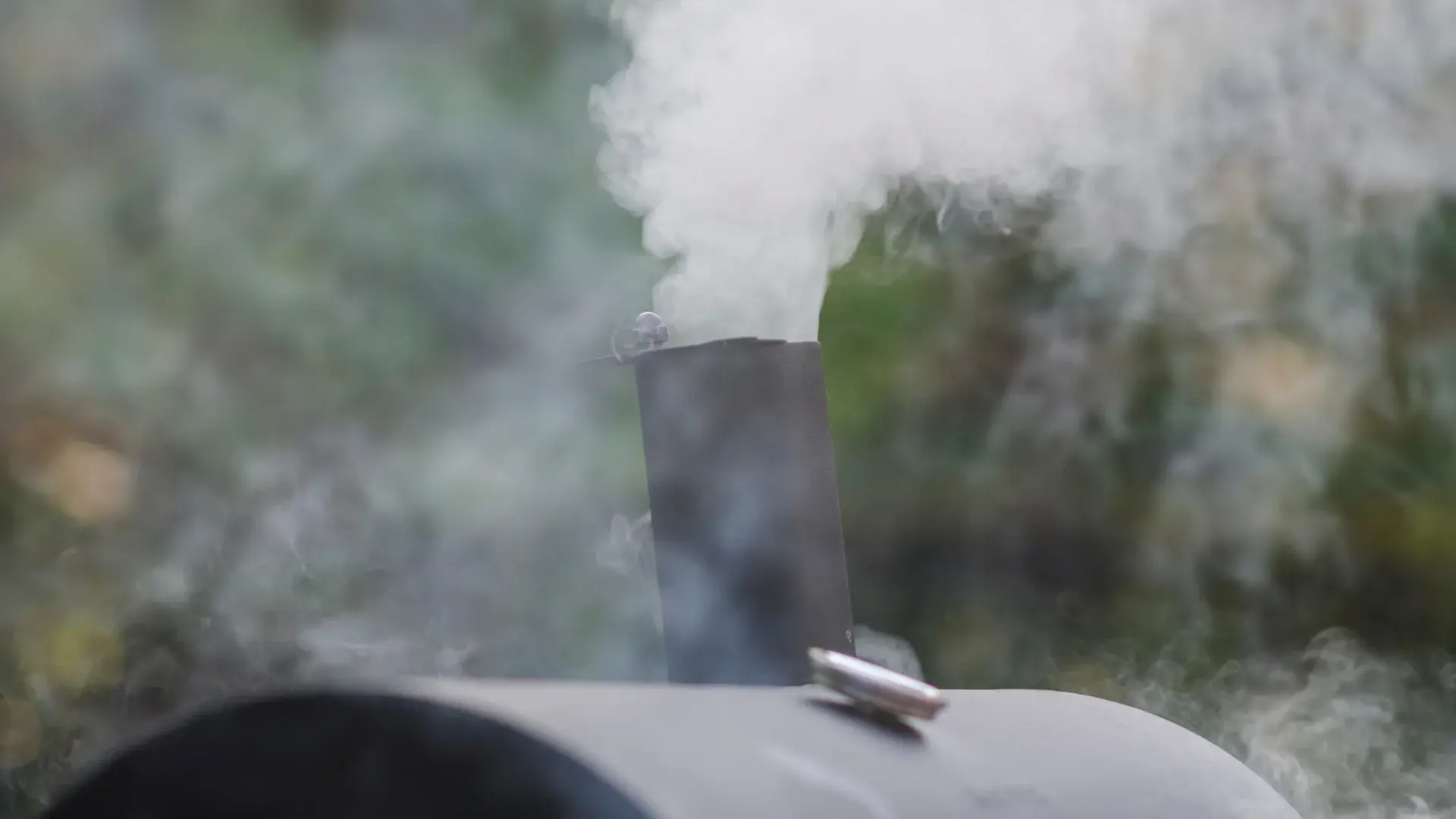 Smoke billowing from a meat smoker. 