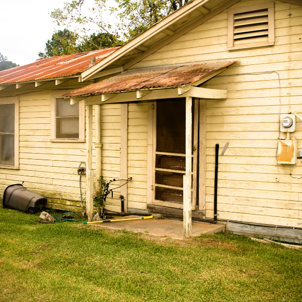 An image showing a house with worn or damaged siding.