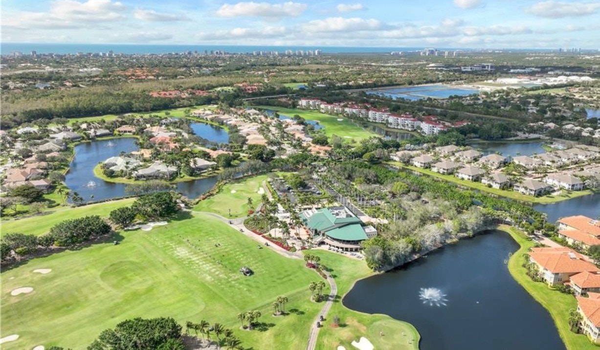 The image showcases the tennis courts and recreational facilities at the Pelican Marsh community center in Naples, Florida, surrounded by lush landscaping. Residents enjoy access to premier amenities, including a community pool and outdoor dining options, all within walking distance of Pelican Marsh homes.