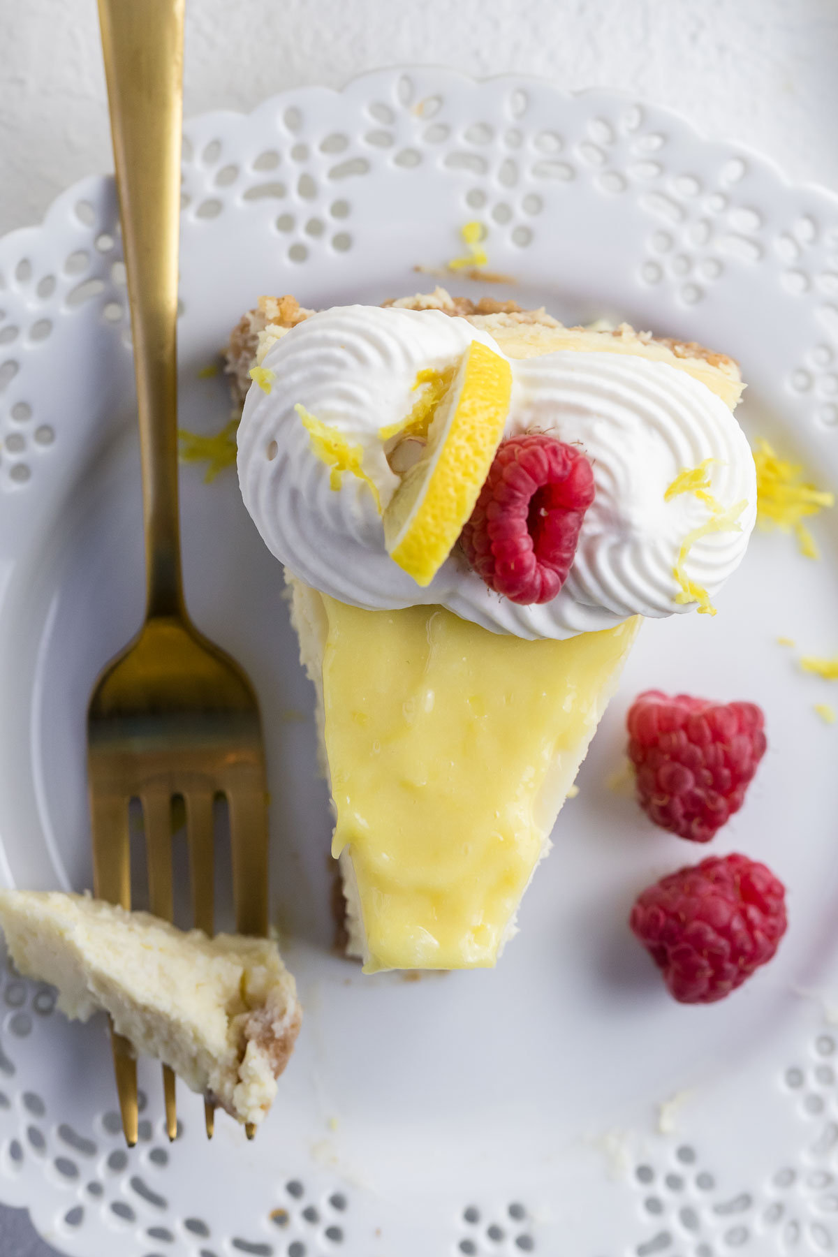 top down view of a slice of lemon cheesecake on a plate with a fork