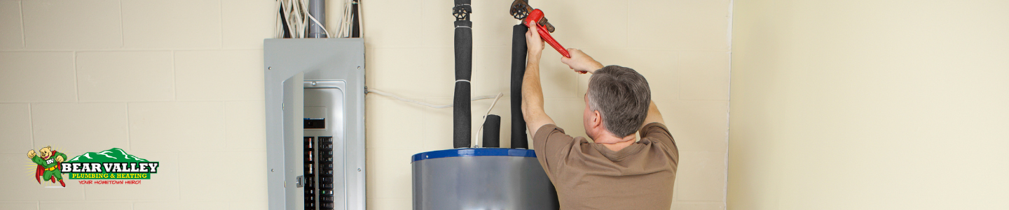 Technician checking the pilot light on a gas water heater, demonstrating the importance of regular maintenance for safe and efficient water heater operation.