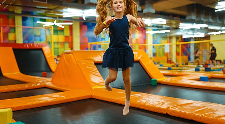 A little girl jumping on a trampoline.