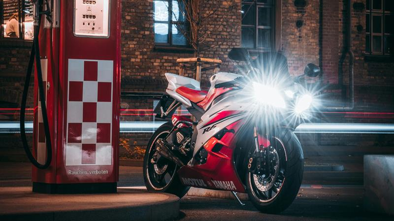 Red and white sport bike next to red and white fuel pump.