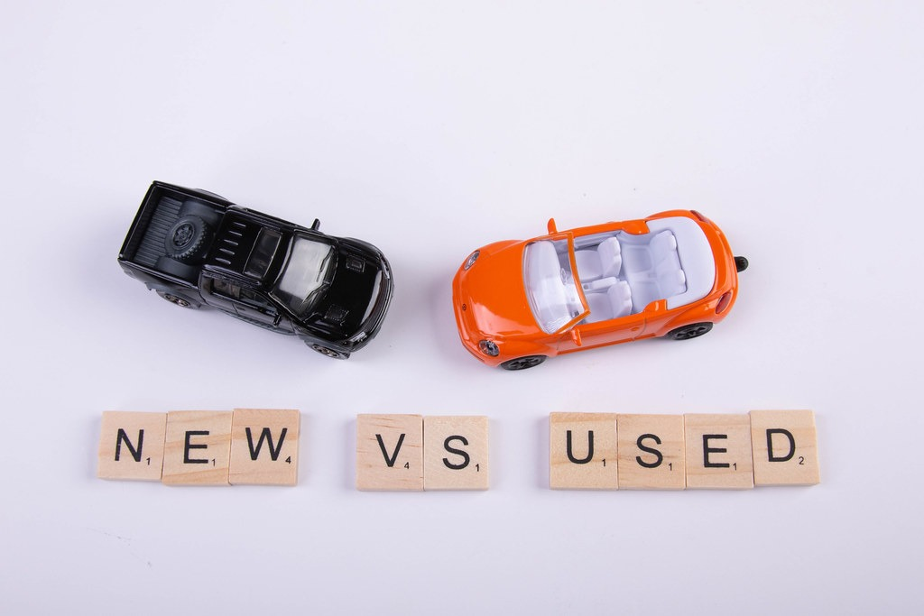 A black and red toy car with a 'new" vs. 'used" word blocks