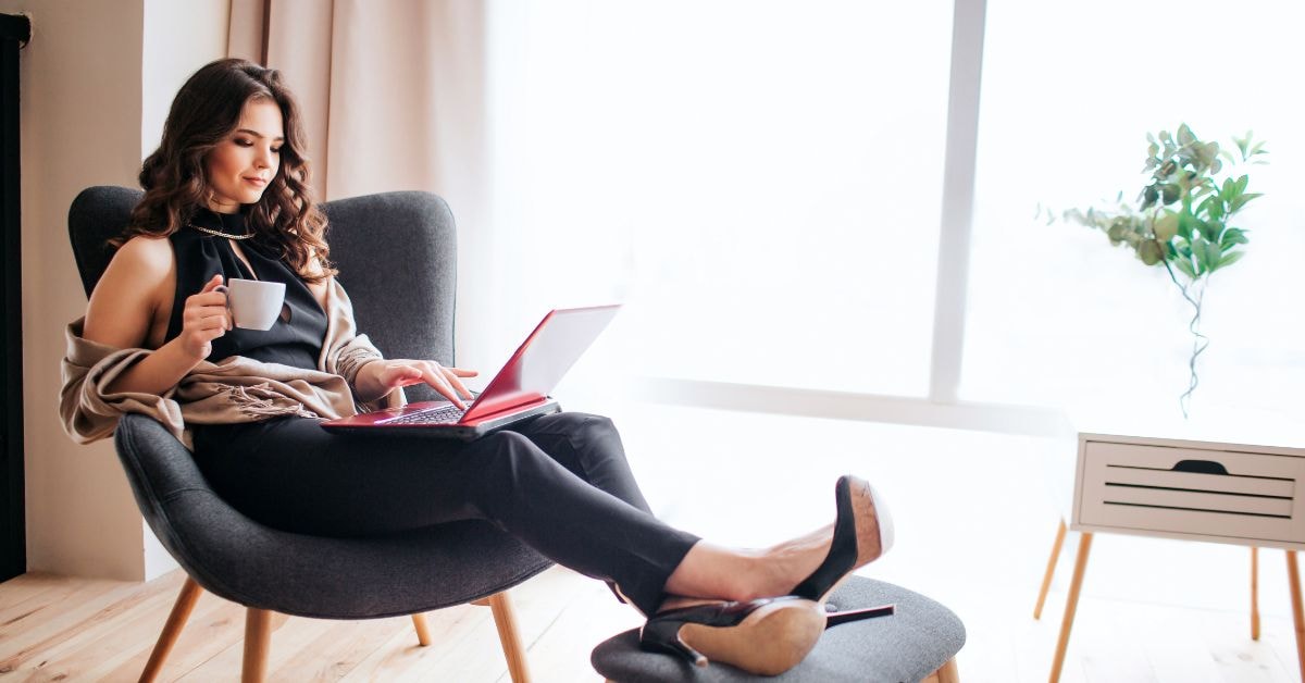 Woman researching how to file state taxes only on her laptop, seated comfortably with a coffee.