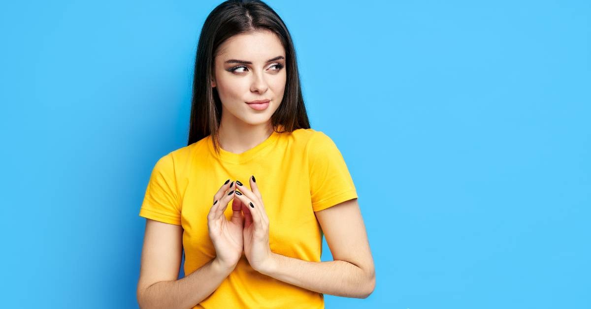 A woman in a yellow shirt thoughtfully considers her financial plan example on a blue background.