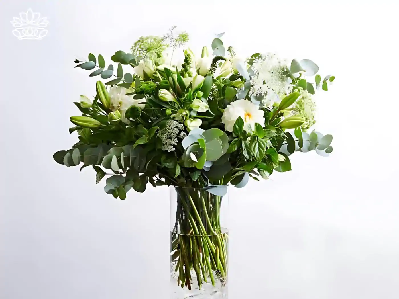 A stunning floral arrangement featuring an array of white blooms, lush green leaves, and elegant eucalyptus, all beautifully presented in a clear glass vase. This sophisticated bouquet exemplifies freshness and grace, ideal for various occasions. All Flower Arrangements Collection. Fabulous Flowers and Gifts.