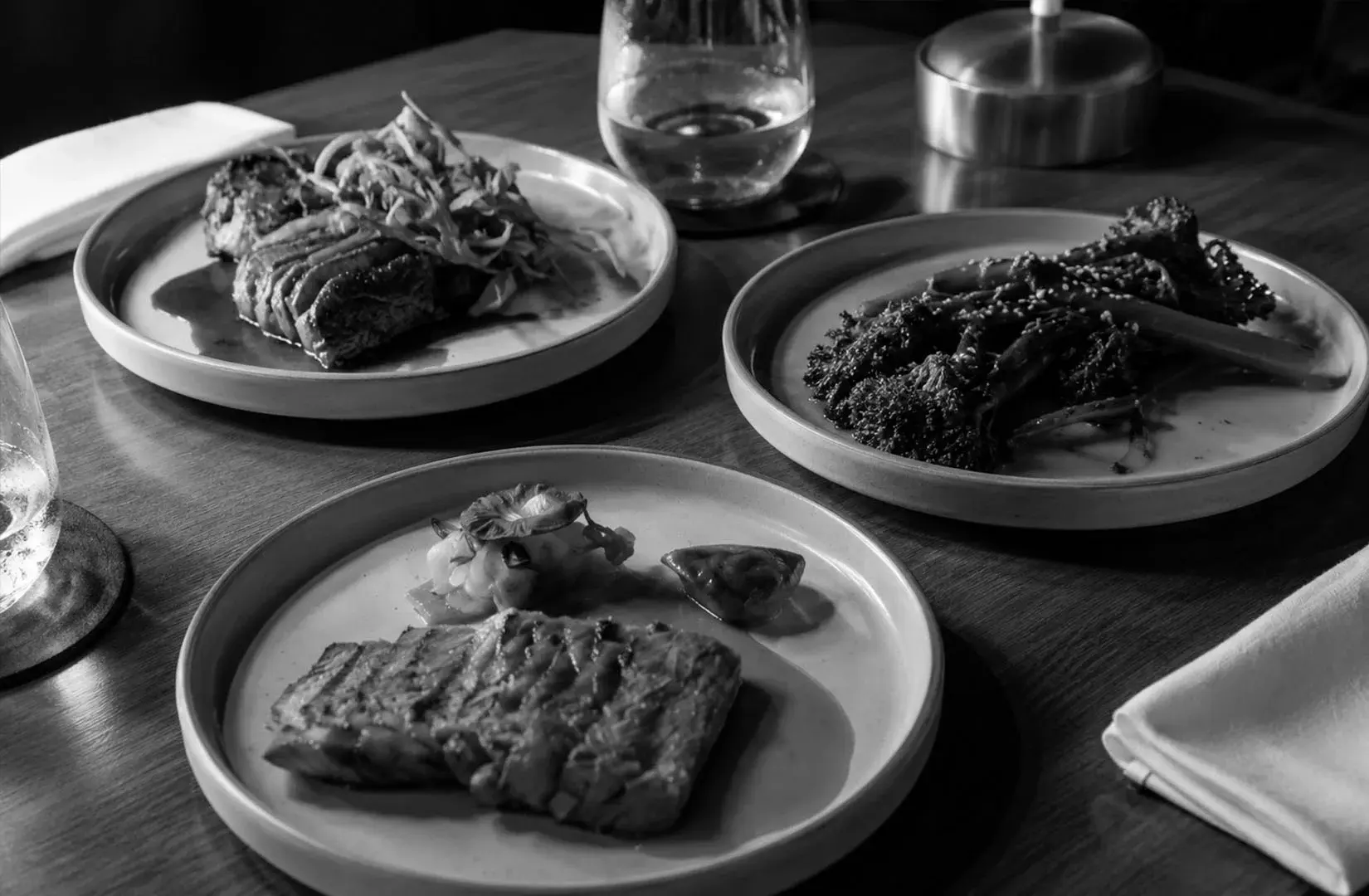 Gourmet steak, vegetables, and seafood dishes arranged on a restaurant dining table.