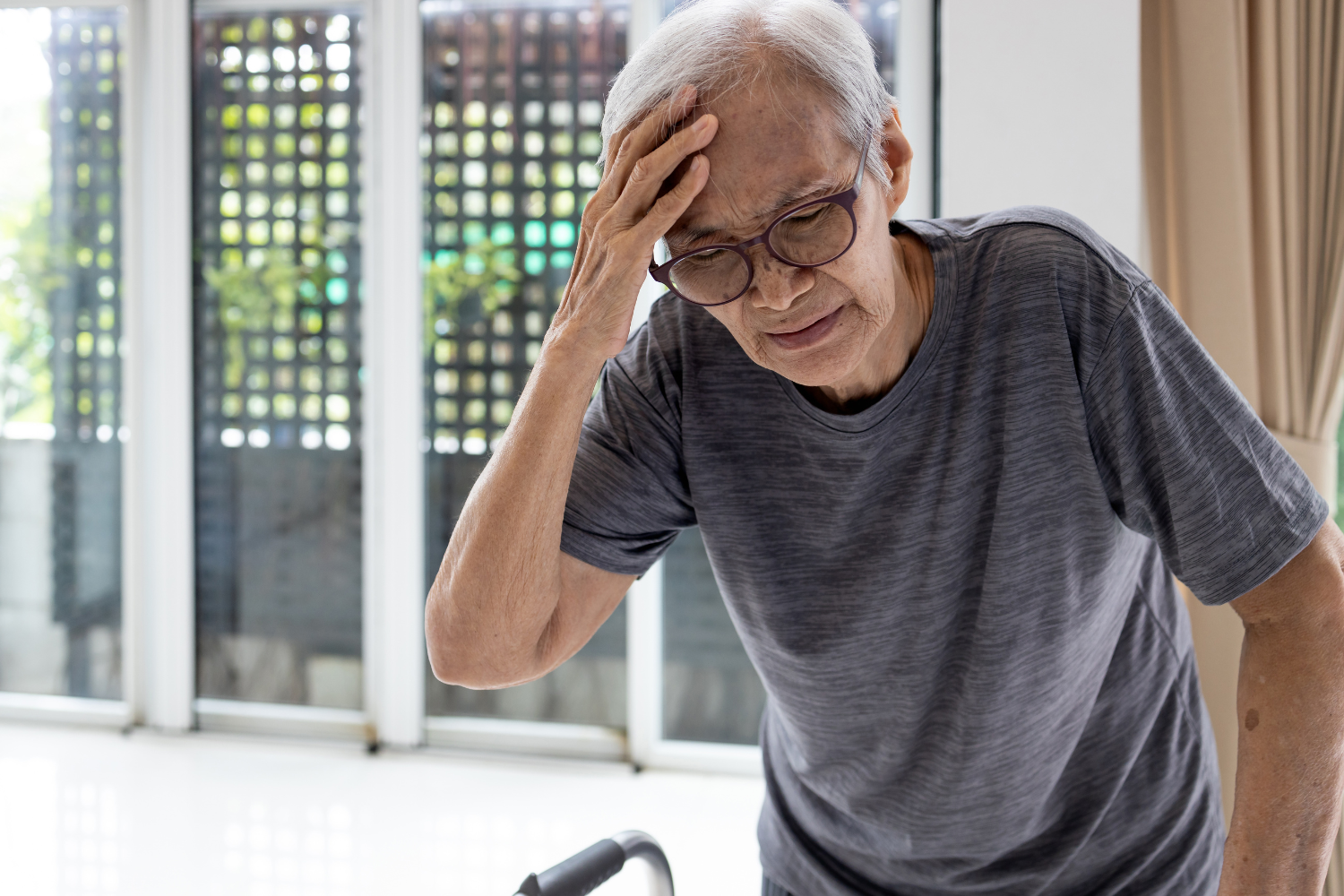Elderly man holding head due to being dizzy.