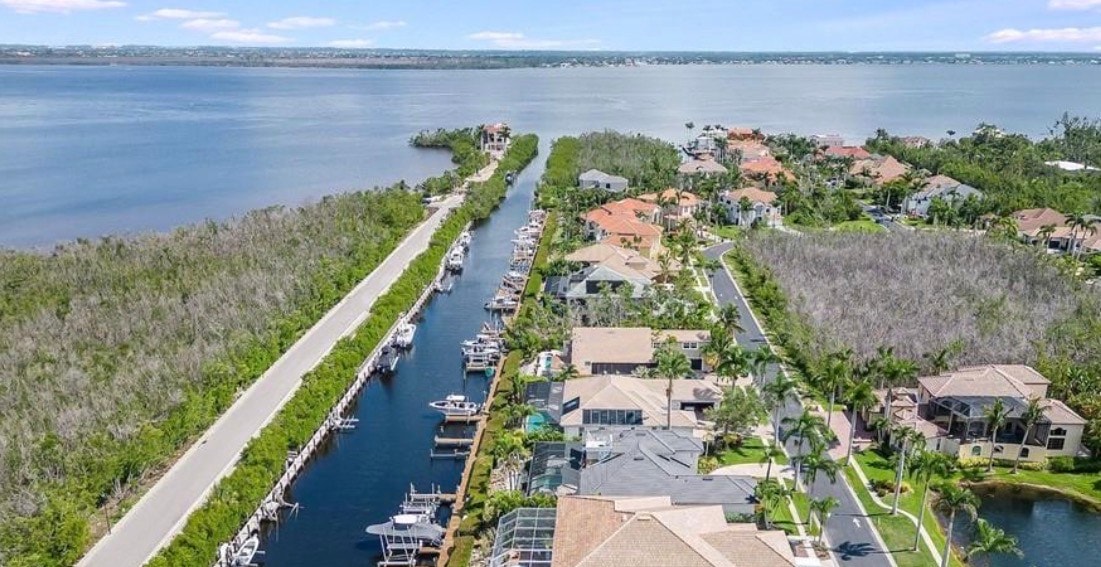 The image depicts luxury boats moored at private docks, with upscale waterfront homes in the background, showcasing the serene lifestyle of a boating community in Fort Myers, Florida. This scene highlights the beautiful waterfront views and the dedicated boat docks that are characteristic of the Catalpa Cove real estate.