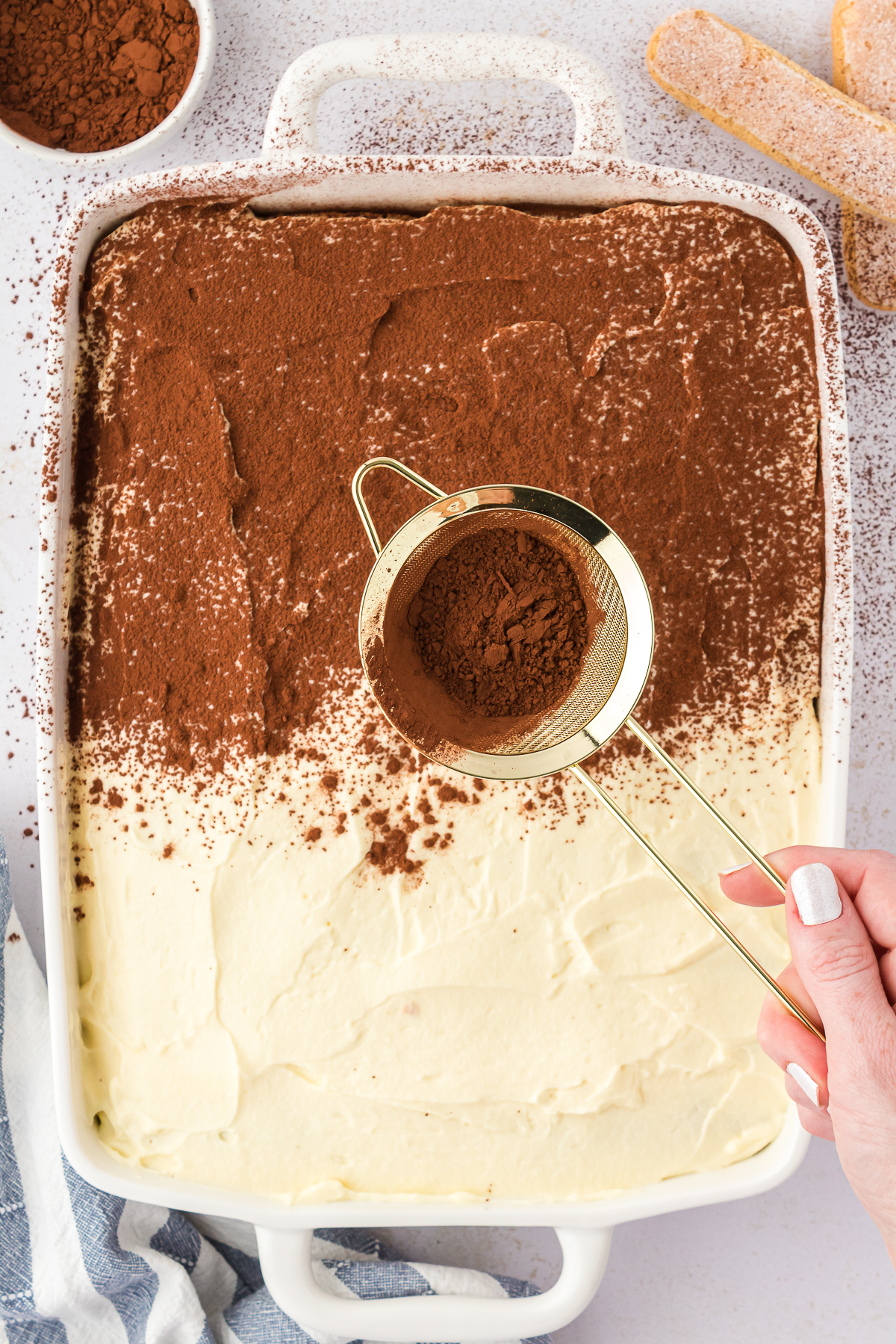 cocoa powder being dusted on top of tiramisu