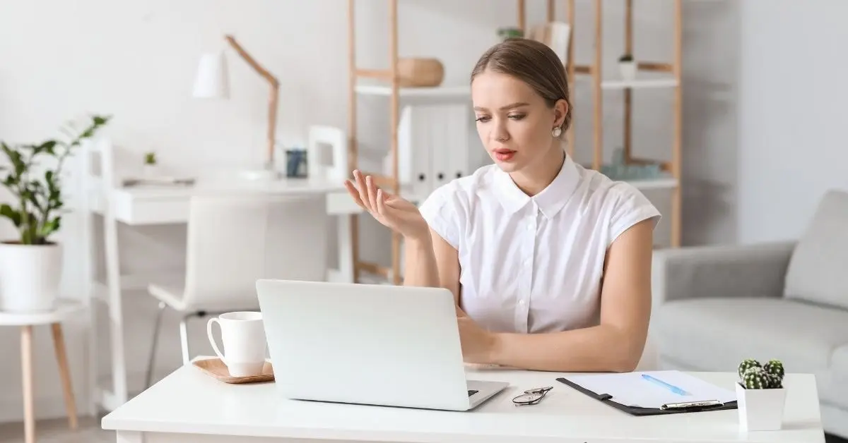 A concerned woman reviewing tax time information on her laptop at a home office desk.