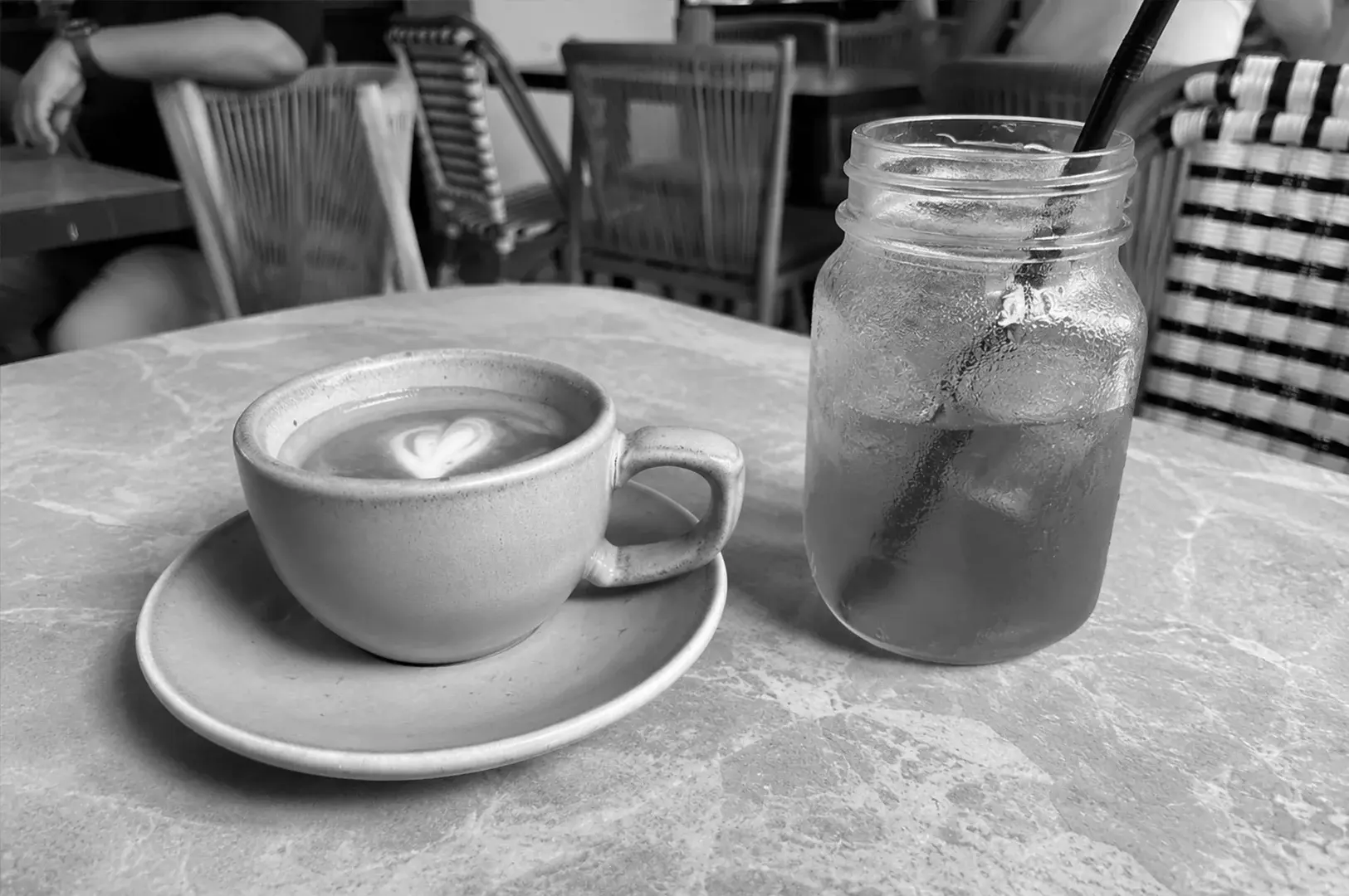 Cappuccino and iced tea served side by side on a café table in a relaxed outdoor setting.