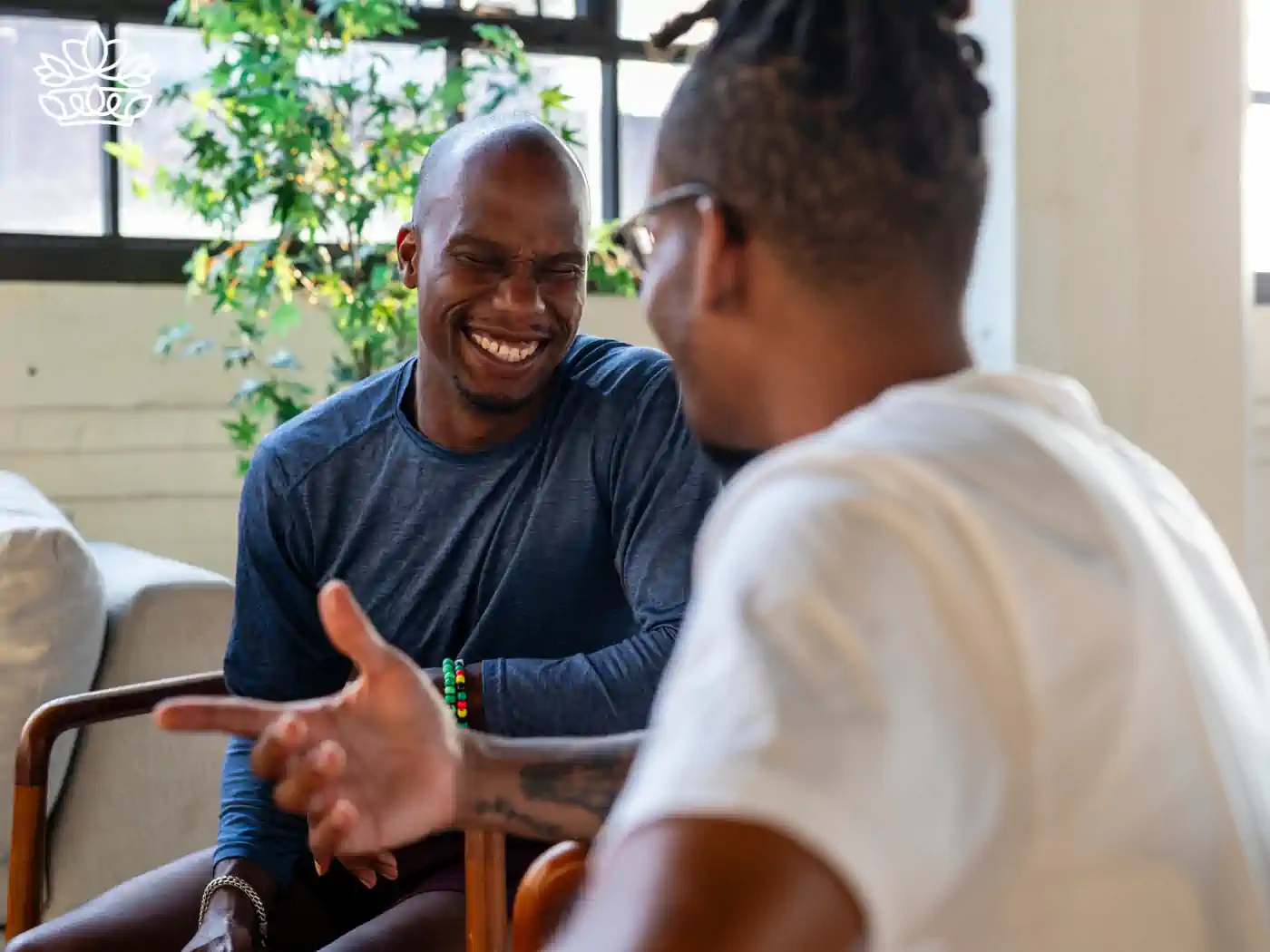 Two men laughing and engaging in a friendly conversation, highlighting the importance of social connections for wellbeing. Fabulous Flowers and Gifts - Health and Wellbeing Collection.