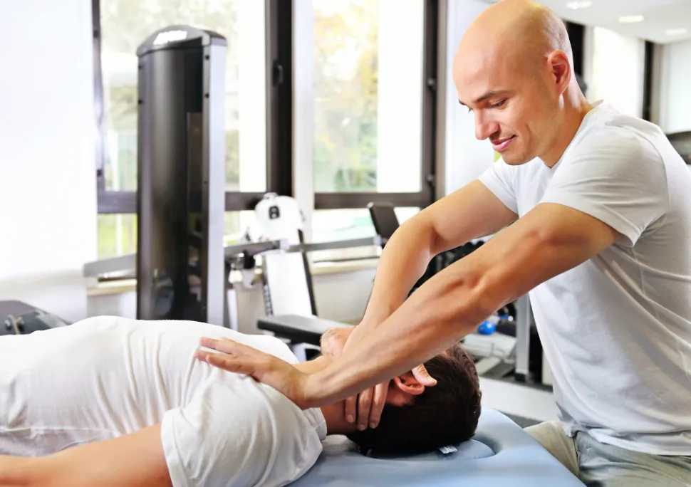 Physical therapist performing hands-on neck treatment for a patient on a therapy table.