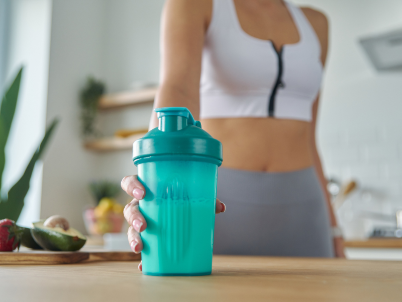 Image of a woman grabbing a shaker cup with EAAs and BCAAs.