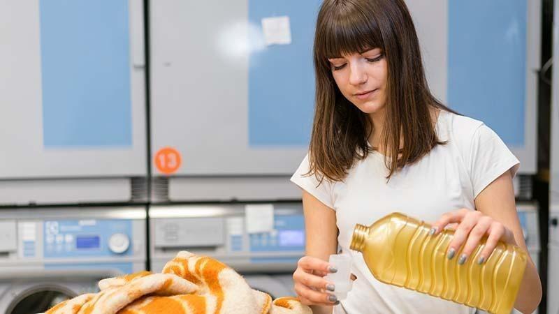 a woman pouring detergent into the cap