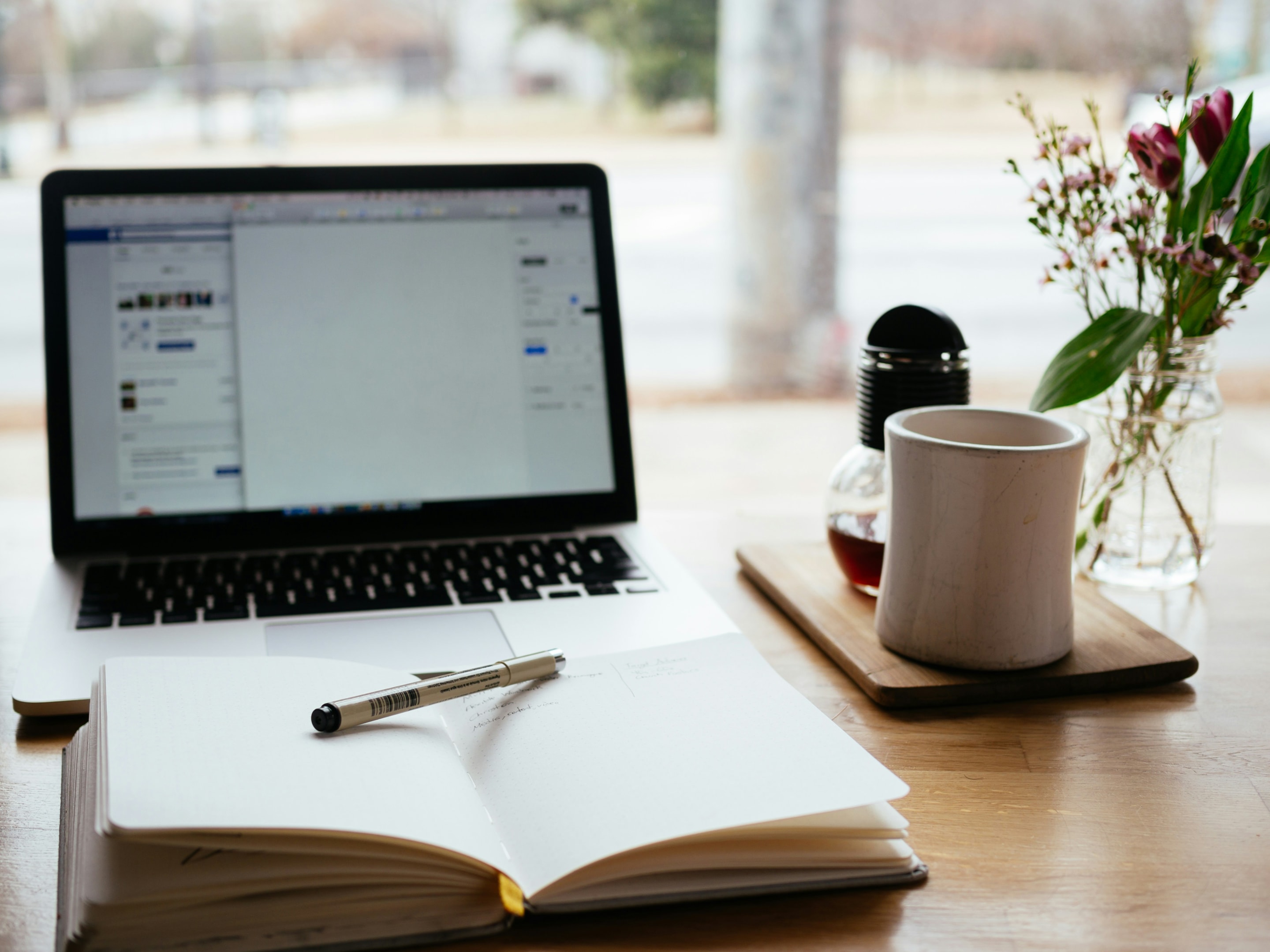 Desk setup of real estate investor with CRM integrations pulled up on his laptop alongside cup of coffee.