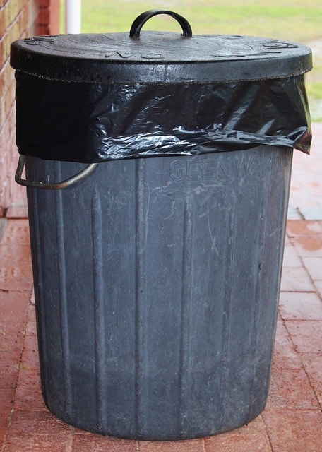 Metal garbage can with plastic bag sticking out