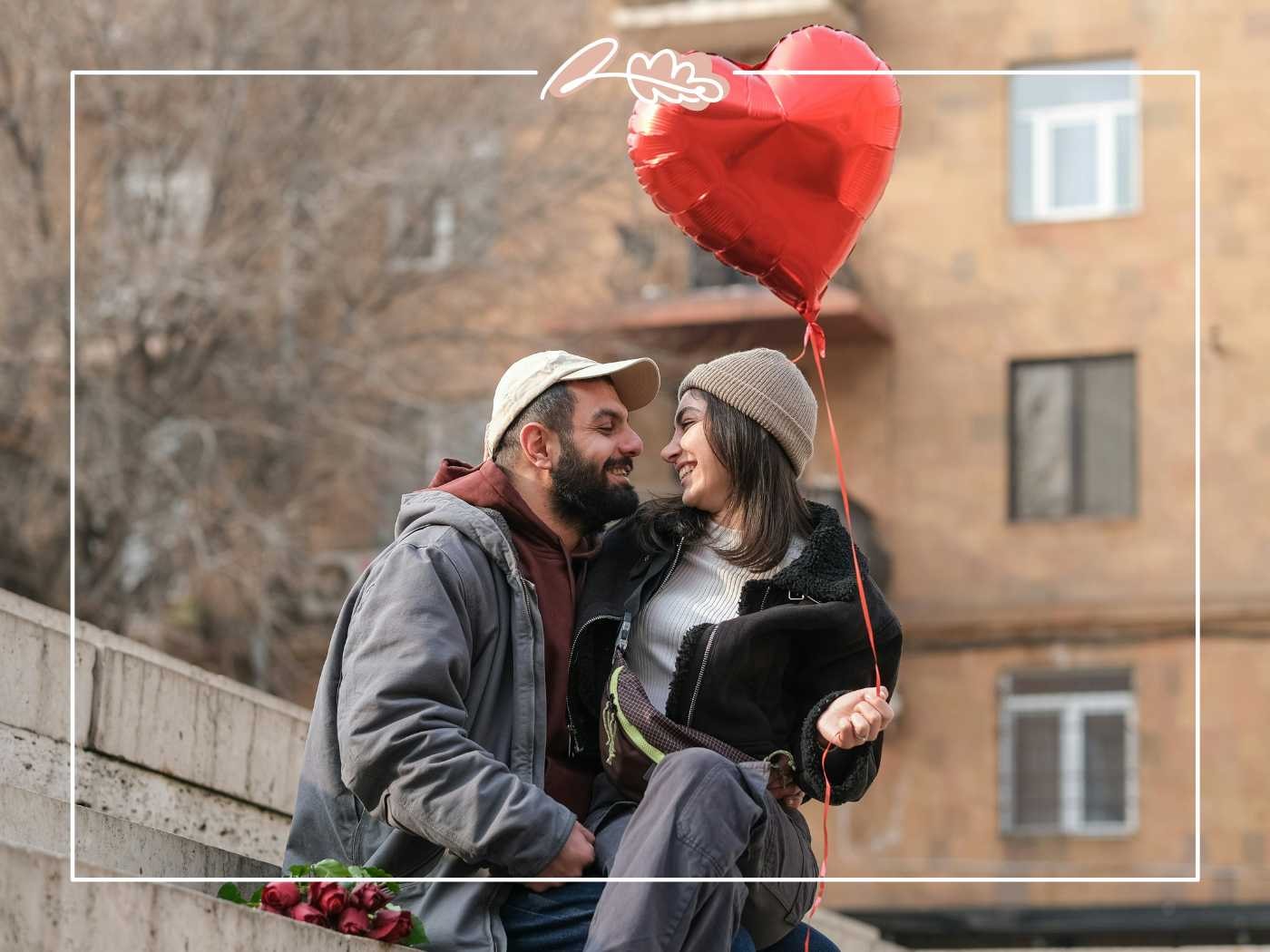 A couple sitting close together on a city street, holding a heart-shaped balloon, symbolizing their love and connection - Fabulous Flowers and Gifts.