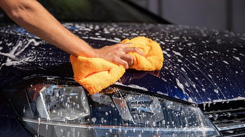 A man washing a blue car
