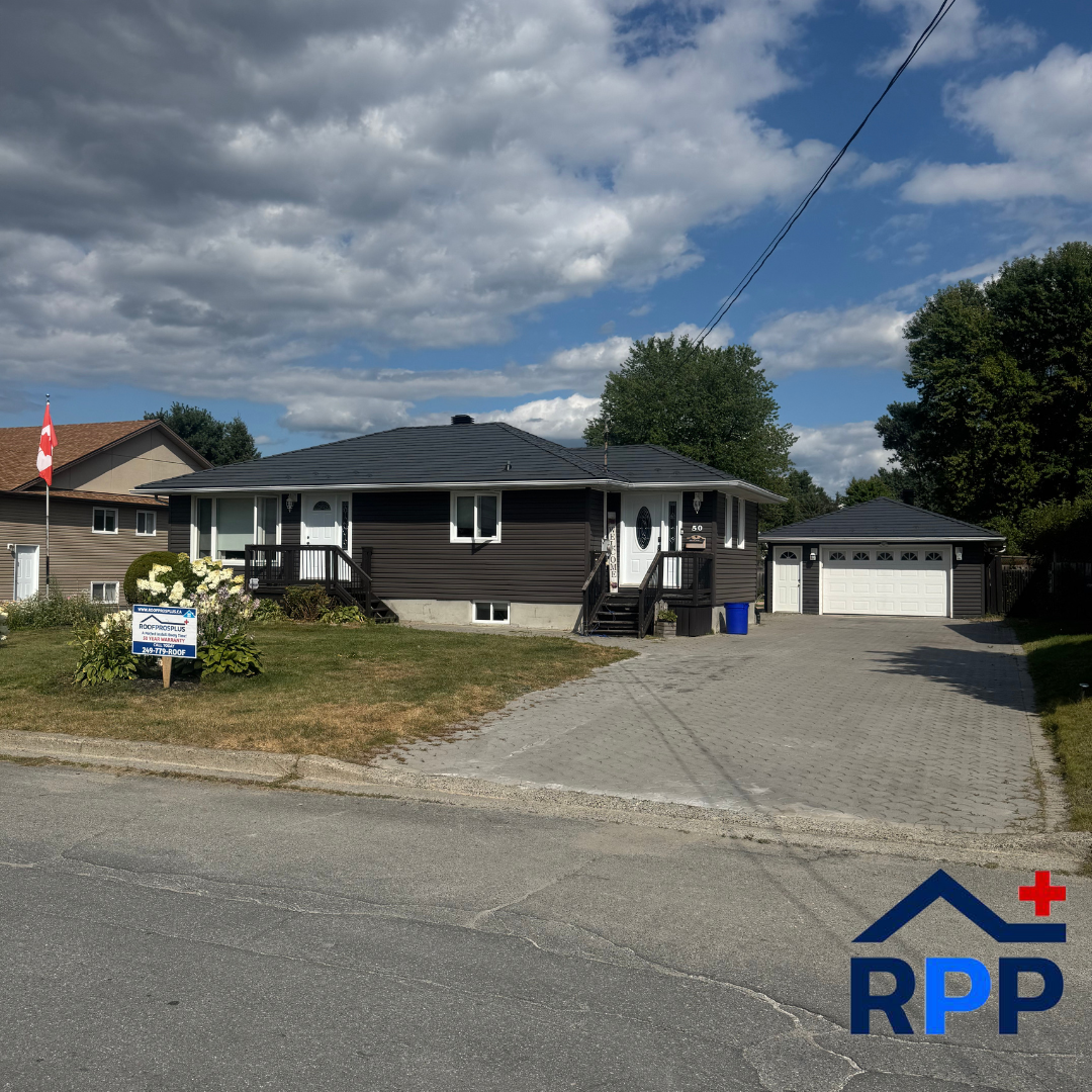 A home with dark siding and a grey metal roof sits under a blue sky with the RPP logo in the bottom right hand corner of the photo.