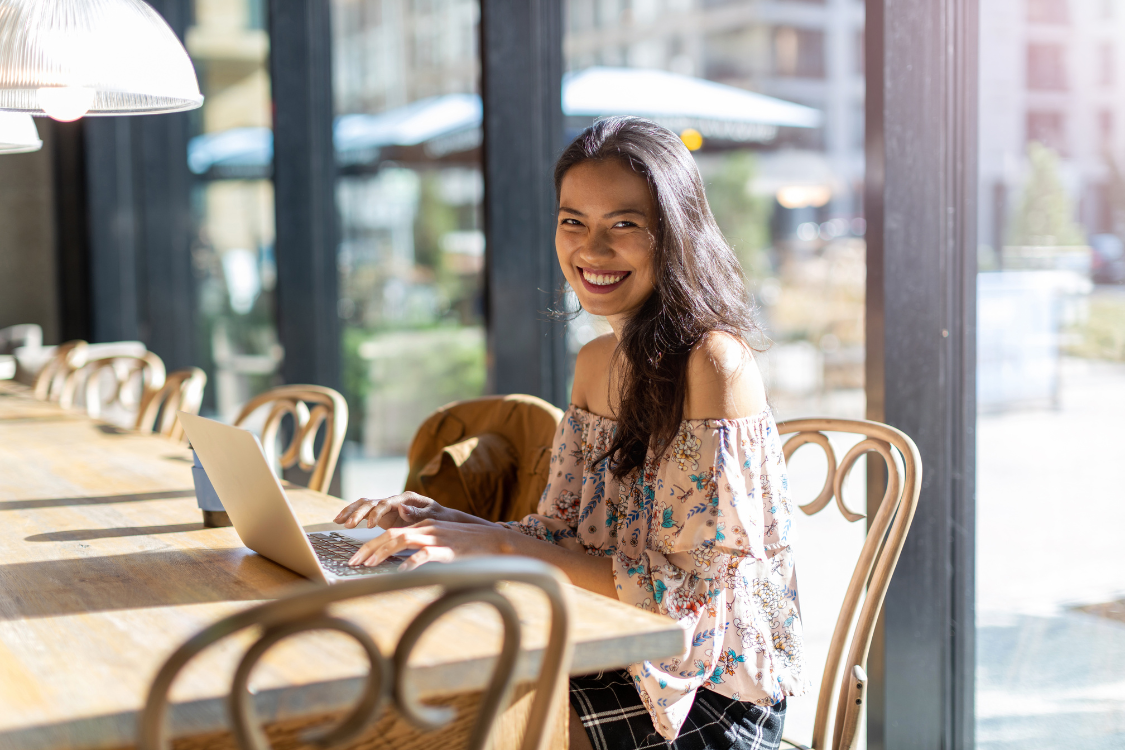 Filipino woman working remotely at cafe with laptop