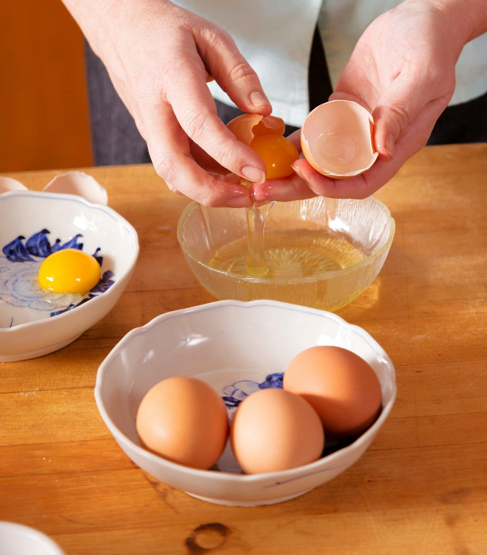 person separating eggs in a small bowl