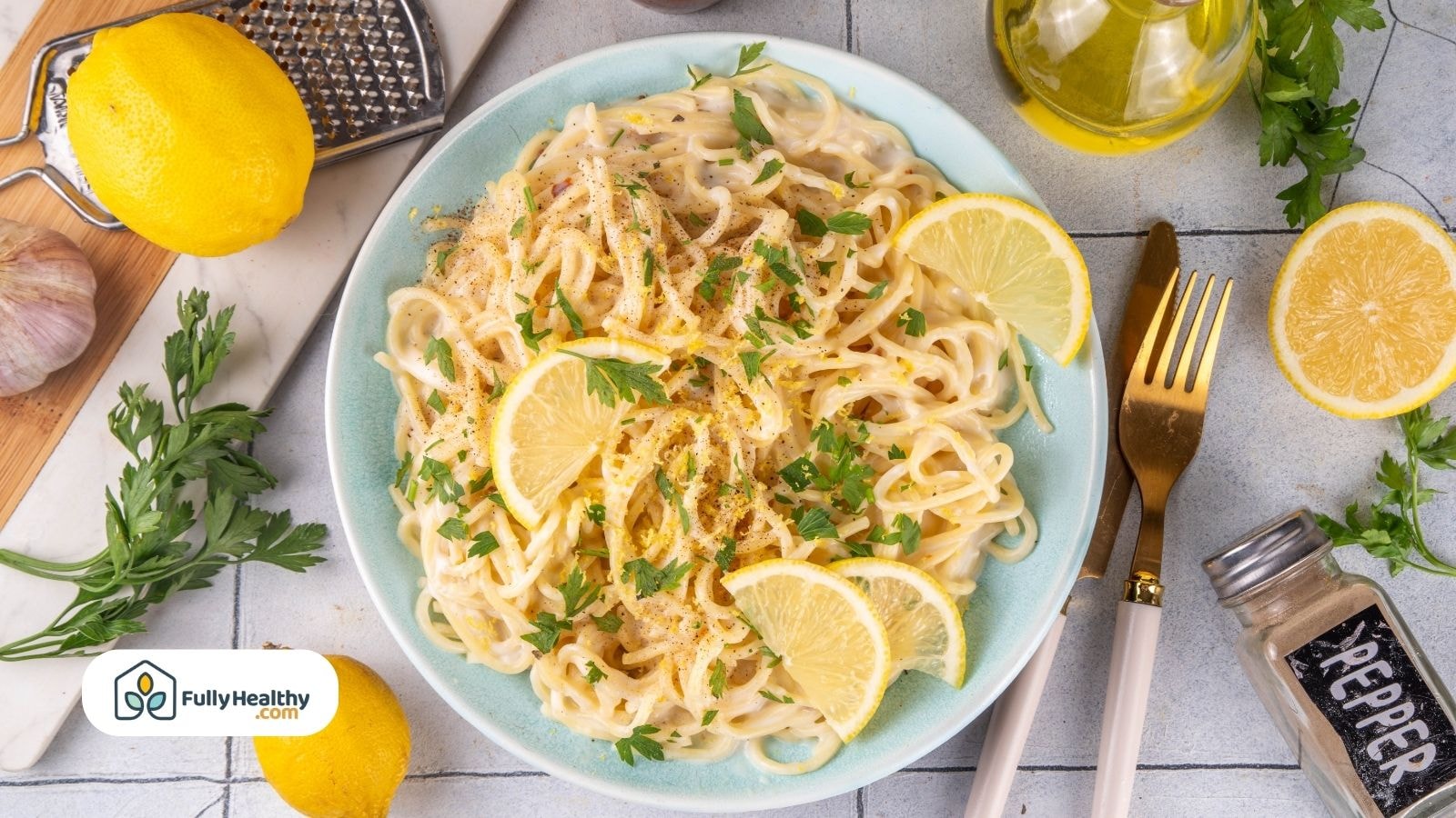 Creamy spaghetti pasta with lemon slices and parsley served on a blue plate with garlic and olive oil