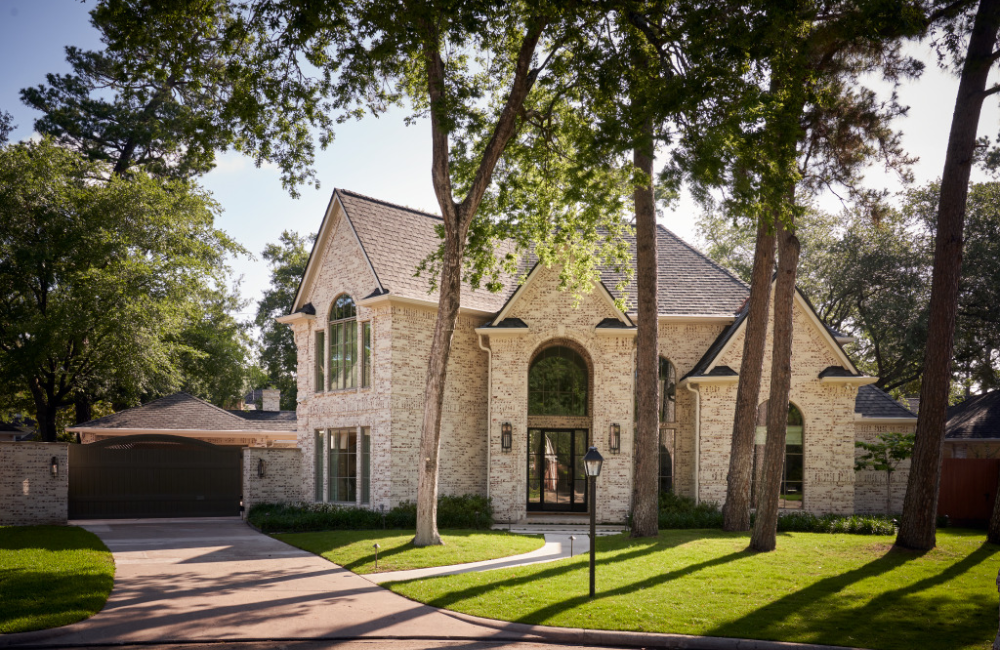 exterior of a white-washed brick house along a tree-lined street