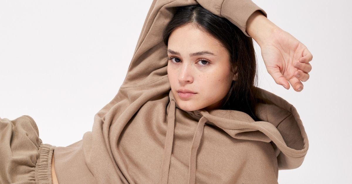 A young woman relaxed in a hoodie, contemplating her net operating profit after tax.