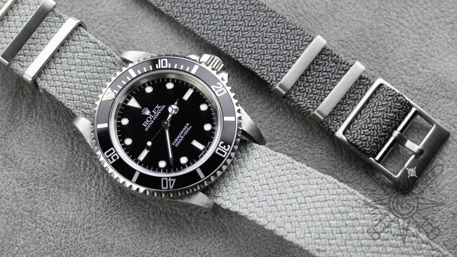 A close-up of a Rolex watch with a perlon strap, showcasing its elegant design.
