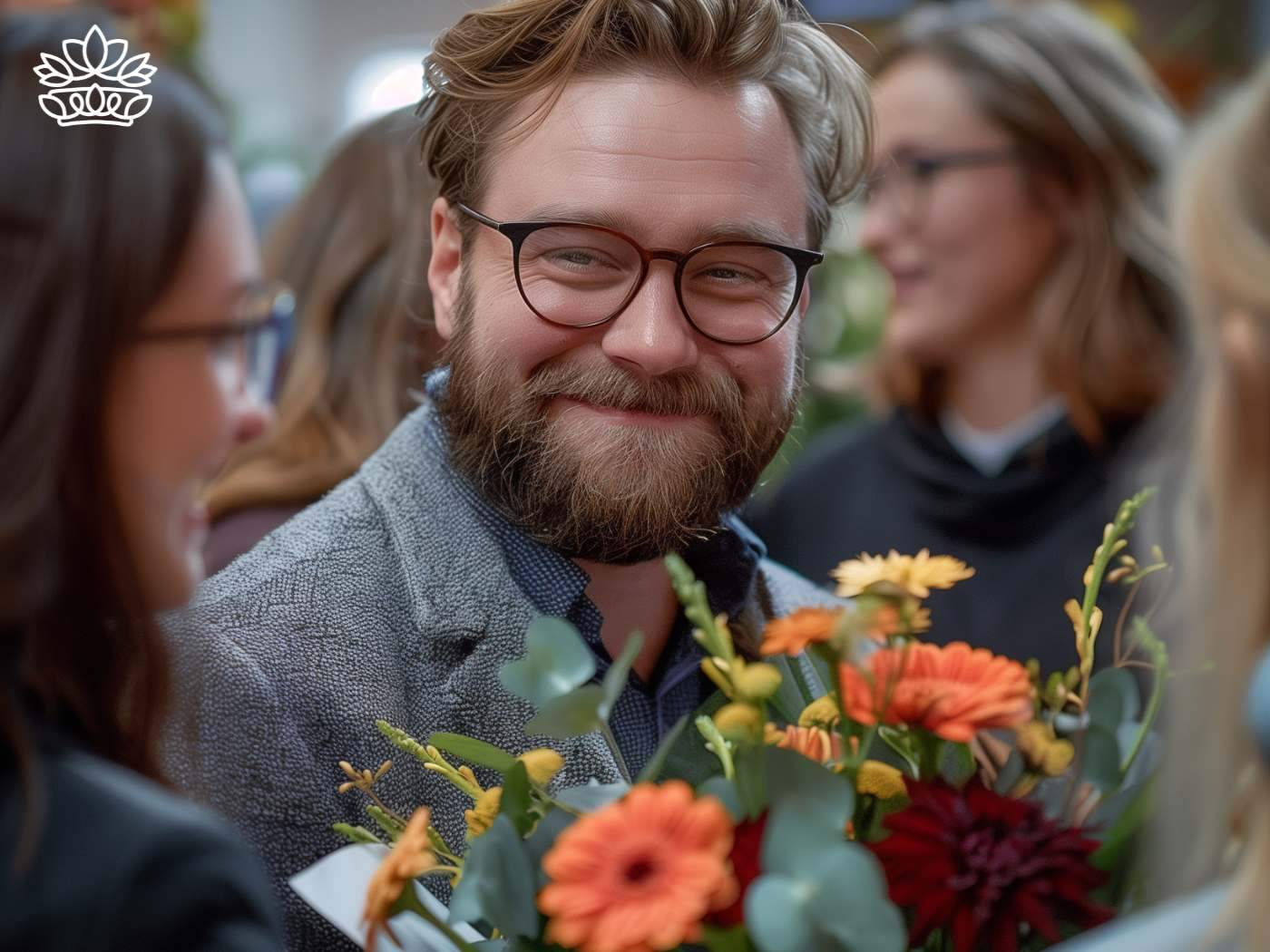 Joyful man with glasses and a welcoming smile at a social gathering, adorned with vibrant autumnal flowers from Fabulous Flowers and Gifts.