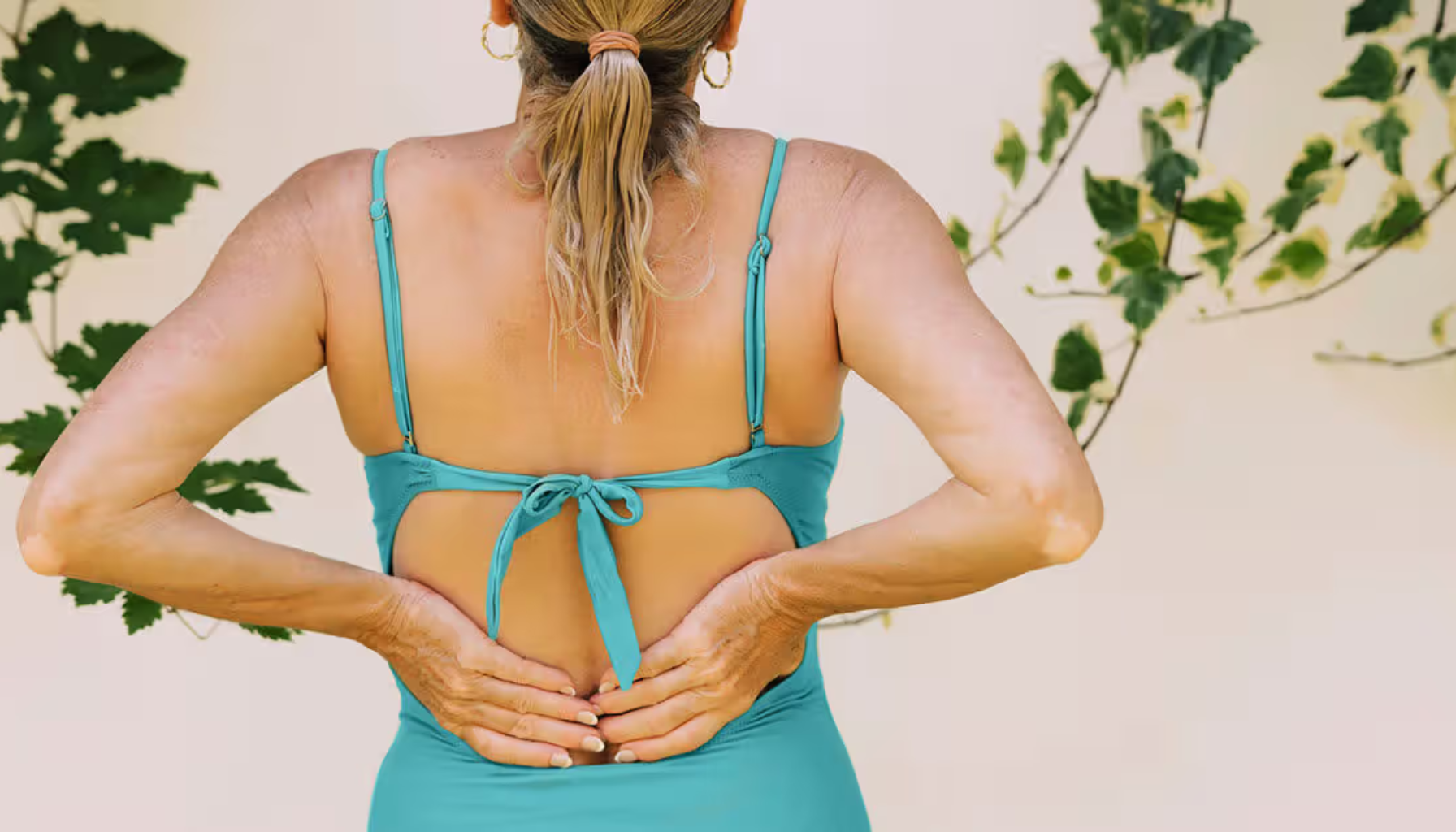 Person holder korsryggen utendørs; behov for vurdering ved vedvarende smerte.